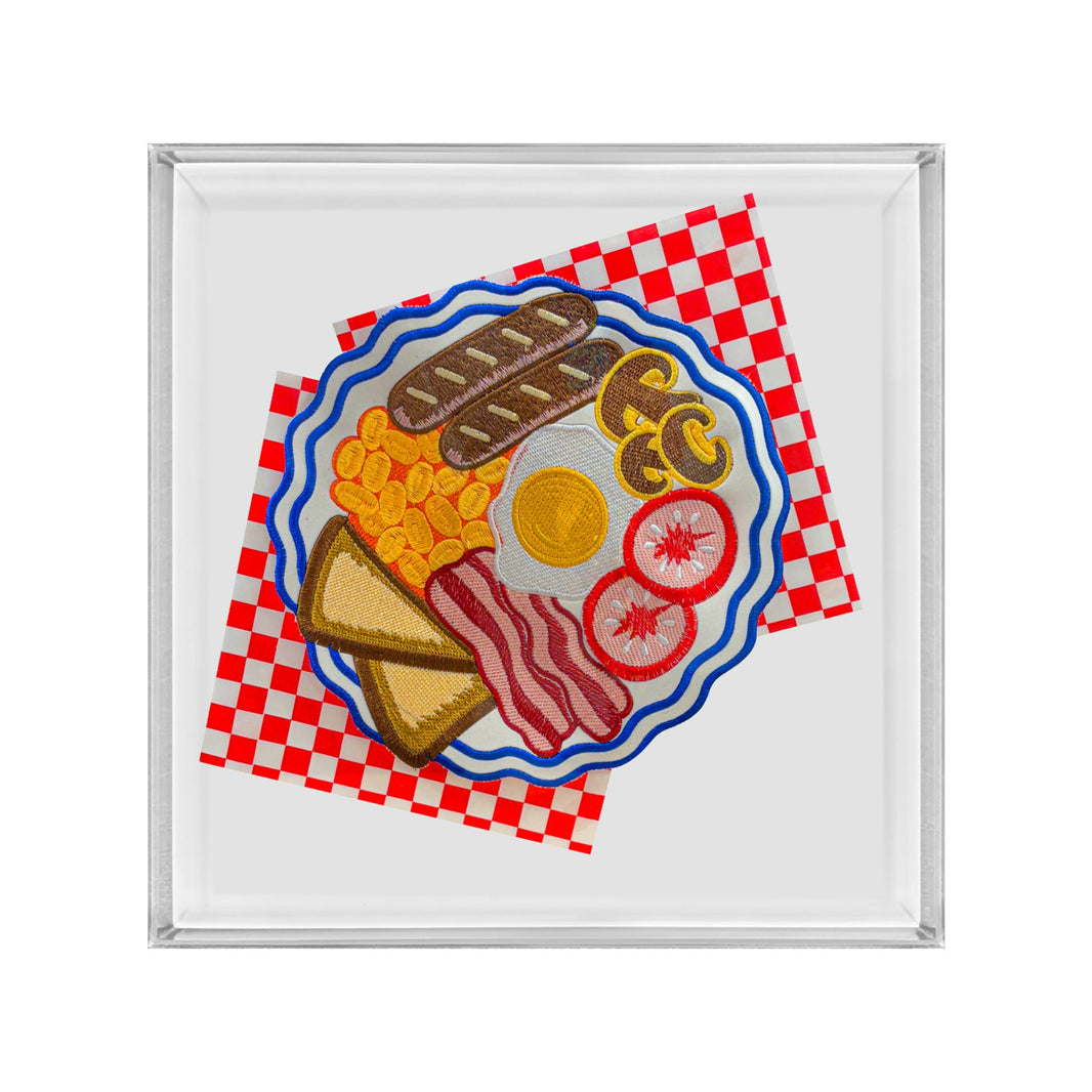A square glass or acrylic tray with a silver-toned rim, featuring a colorful illustration of a breakfast plate with eggs, bacon, toast, beans, and tomato on a red-and-white checkered napkin.
