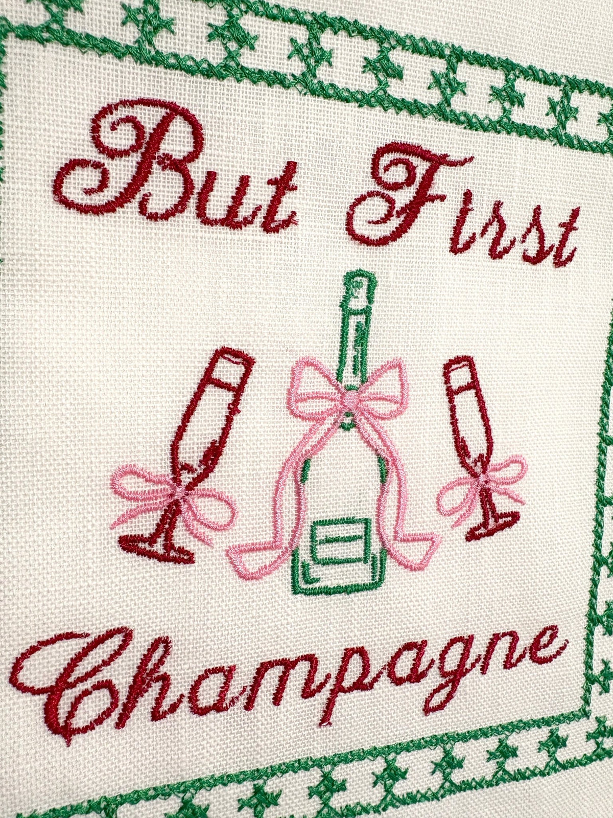 Lillyloves embroidered artwork featuring the phrase "But First Champagne" with decorative floral accents on fabric.