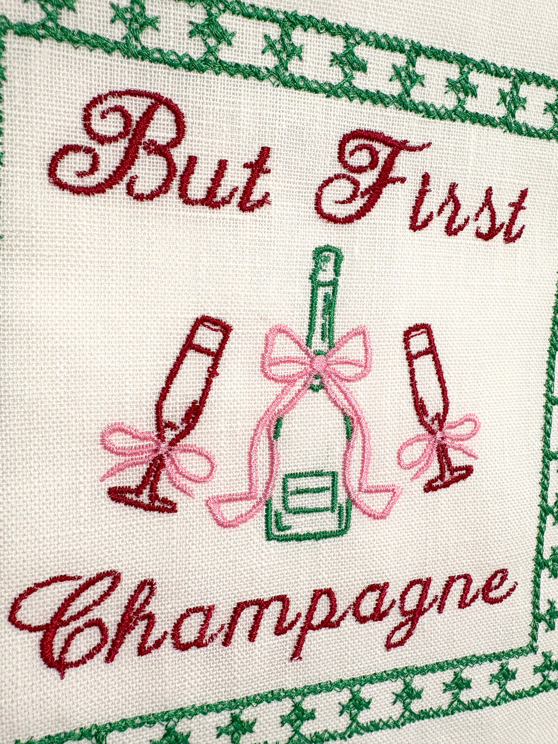 Lillyloves embroidered artwork featuring the phrase "But First Champagne" with decorative floral accents on fabric.