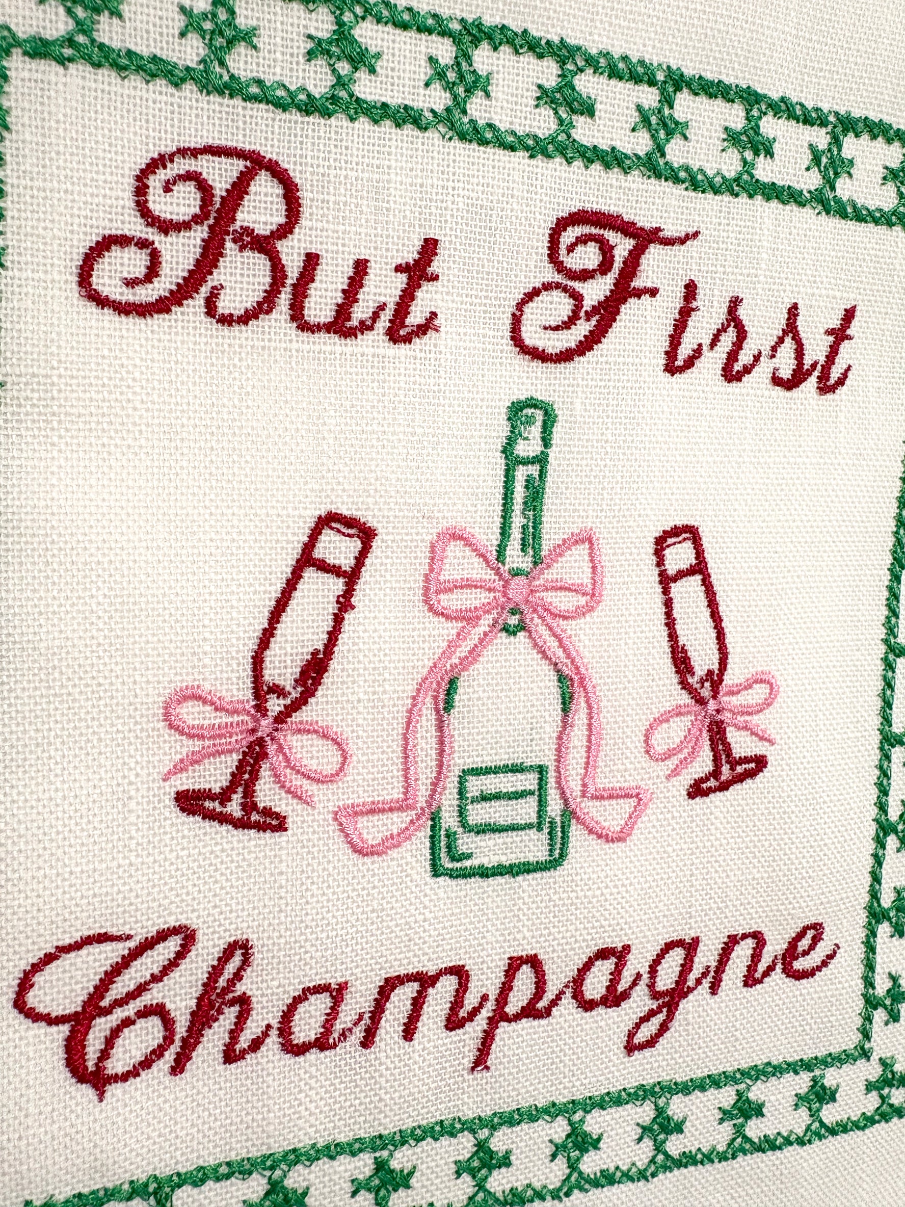 Lillyloves embroidered artwork featuring the phrase "But First Champagne" with decorative floral accents on fabric.