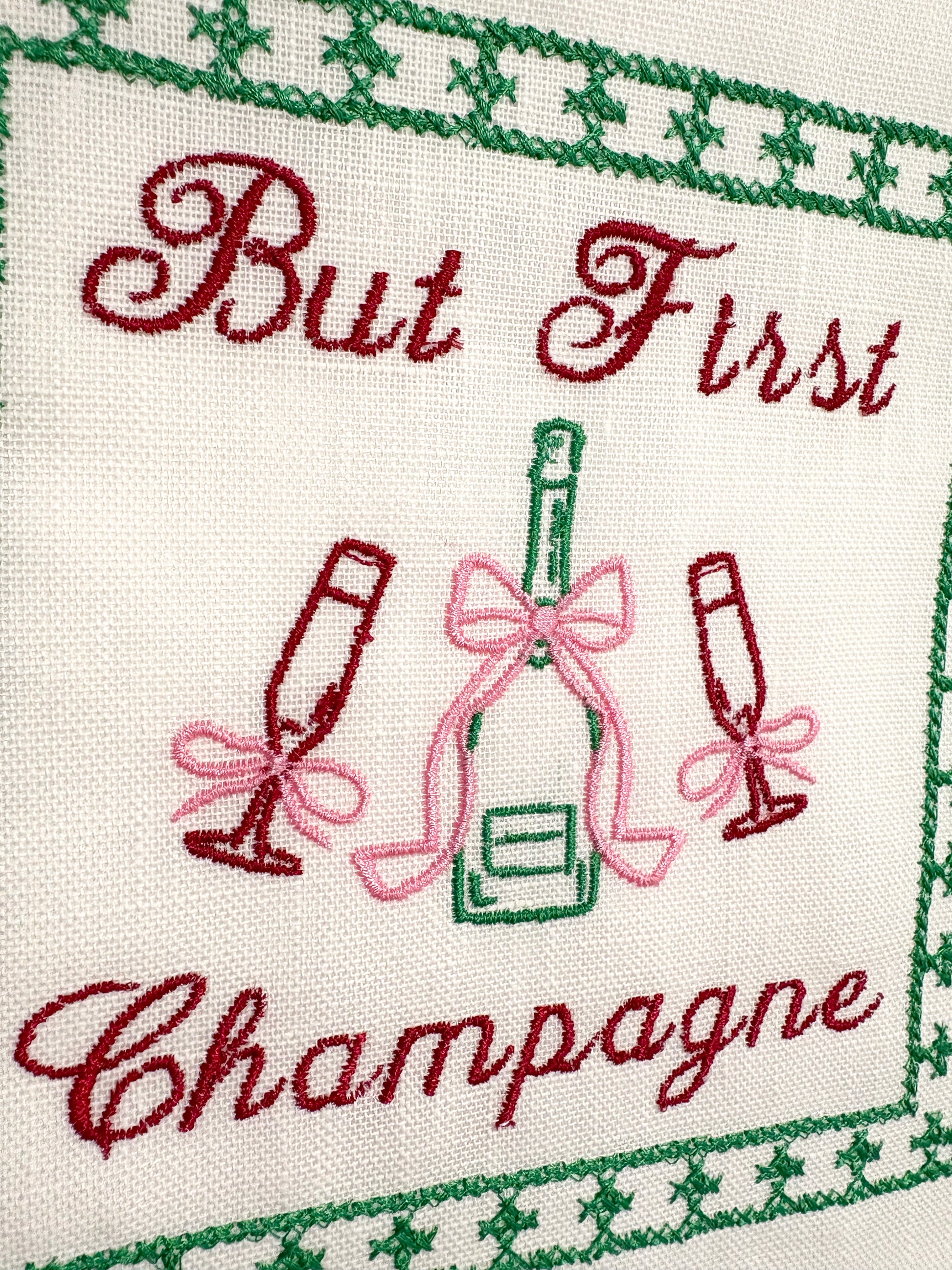 Lillyloves embroidered artwork featuring the phrase "But First Champagne" with decorative floral accents on fabric.