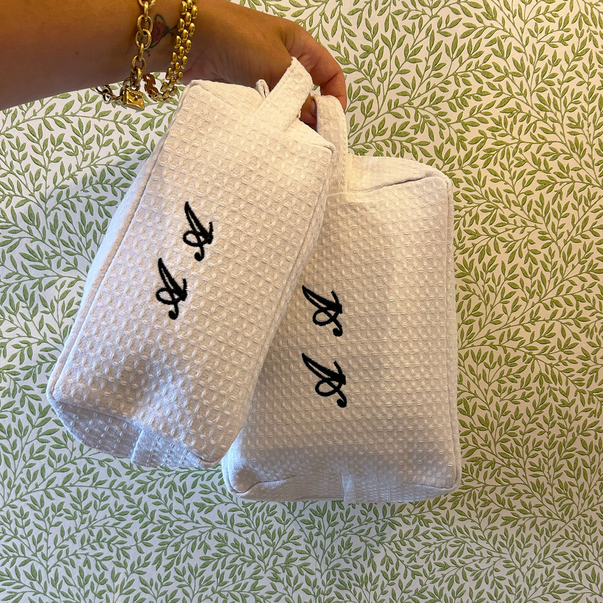 Small Lilly Loves monogramed black and white waffle makeup bag hanging, compact wash bag with elegant design.