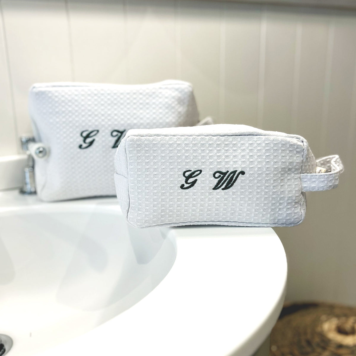 Small black and white monogrammed waffle makeup bag by Lilly Loves with green waffle fabric detail.